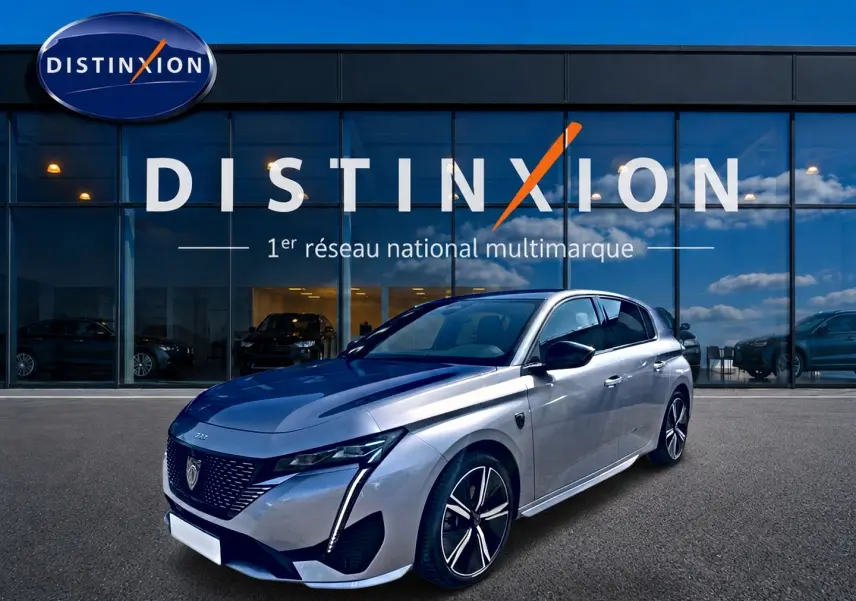 Peugeot 308 gris vue 3/4 avant droit, avec jantes alliage et phares LED distinctifs, devant showroom Distinxion.