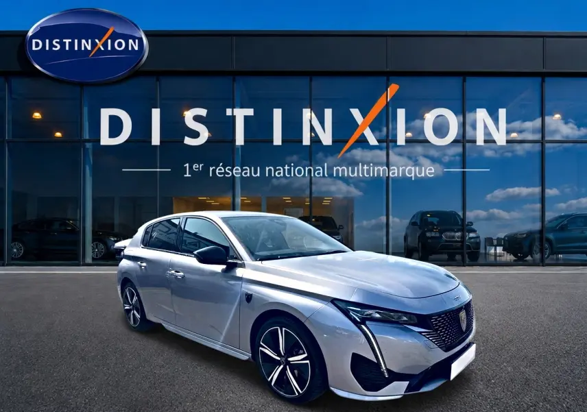 PEUGEOT 308 gris en 3/4 avant droit, avec jantes alu et calandre distinctive, devant showroom Distinxion.