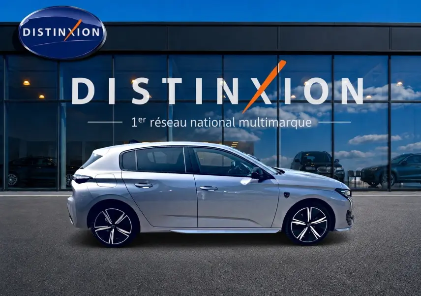 Peugeot 308 gris vue de profil côté gauche, avec jantes alliage distinctives, devant une vitrine Distinxion.