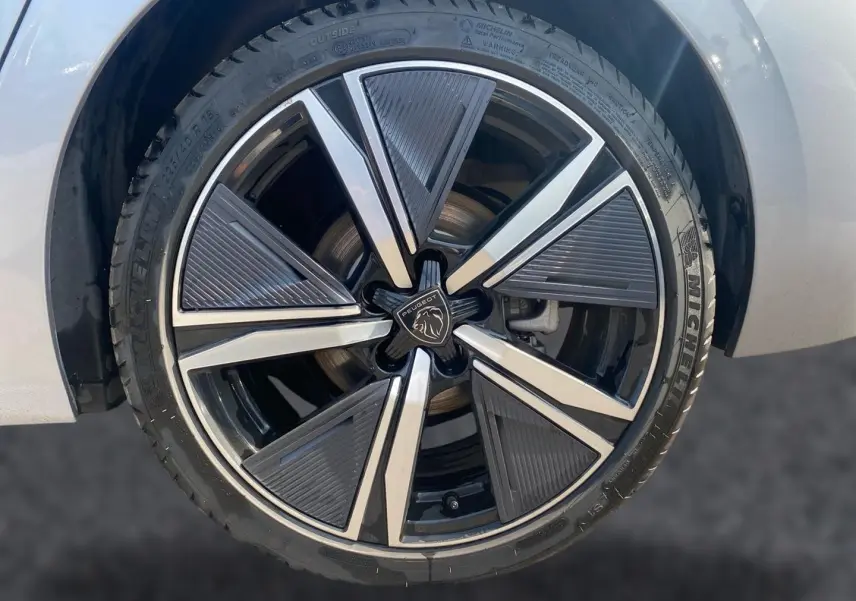 Gros plan sur la jante alu noire et argentée du côté avant gauche d’une Peugeot 308 gris clair.
