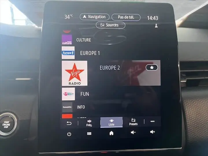 Écran tactile central de la Renault Clio V blanc nacré affichant les stations radio avec bouton Start Engine Stop visible à gauche.
