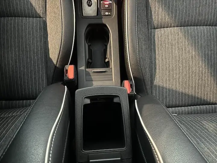 Vue plongeante sur la console centrale et les sièges avant en tissu gris et cuir noir de la Renault Clio V blanche nacrée.