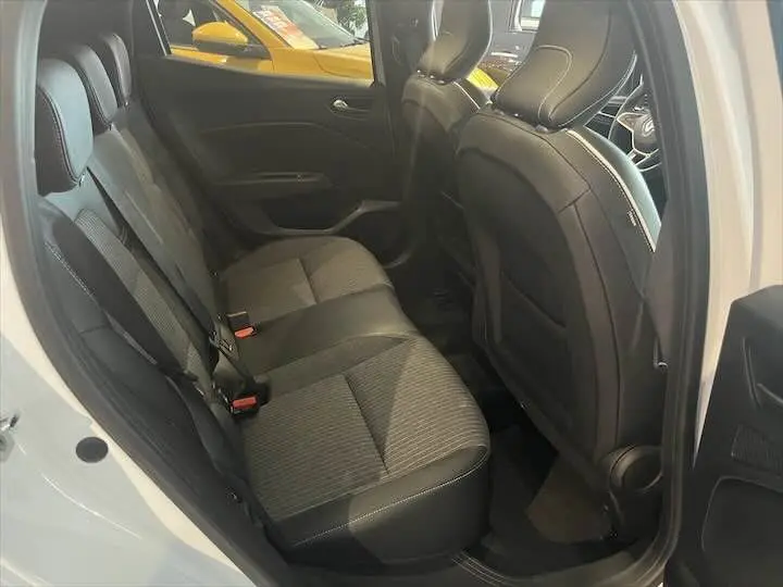 Vue intérieure côté gauche des sièges arrière en tissu noir et cuir sur une Renault Clio V blanc nacré, avec porte ouverte.