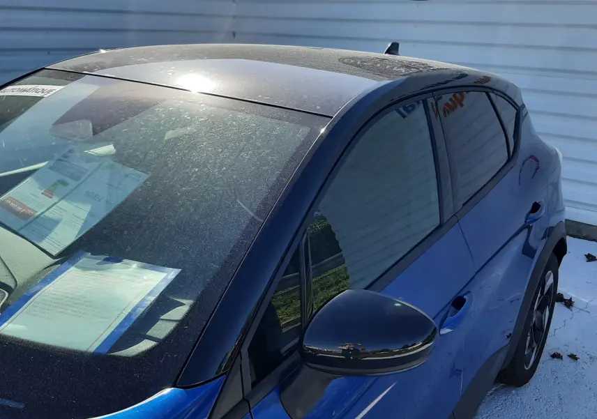 Vue 3/4 avant droit du Renault Captur E-Tech Hybrid 2024 bleu Iron avec toit noir et rétroviseur assorti.