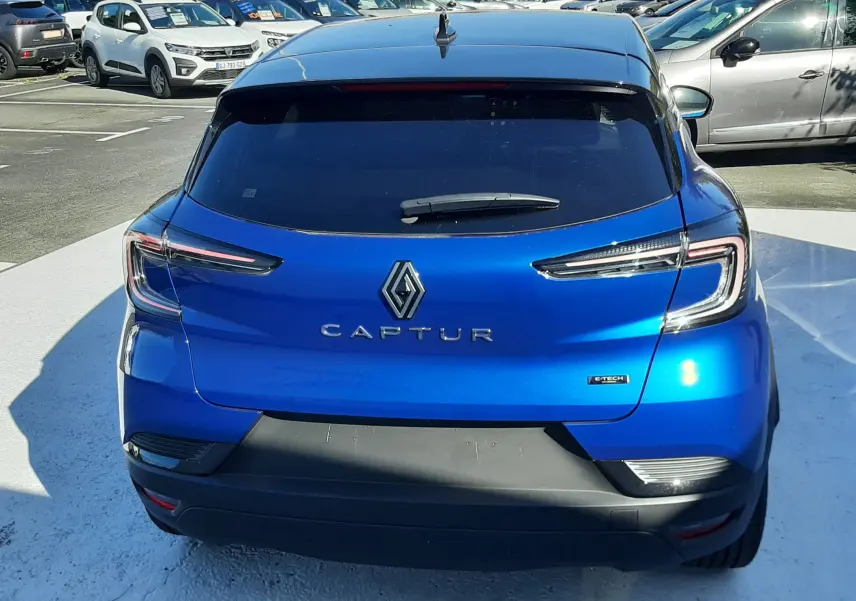 Vue arrière d'un Renault Captur E-Tech Hybrid 145ch en bleu Iron avec toit noir, mettant en valeur ses feux LED distinctifs.