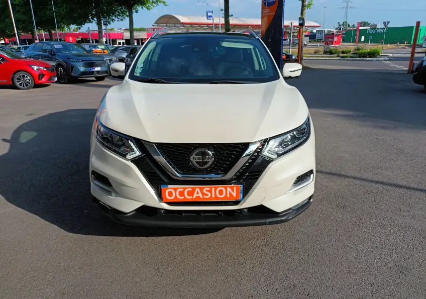 Vue frontale d'un Nissan Qashqai blanc nacré 2019 avec plaque "OCCASION" en orange sur un parking extérieur.