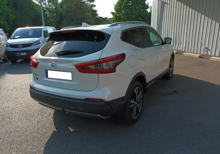 Nissan Qashqai blanc nacré vu de l'arrière droit, avec feux arrière LED et jantes alliage bicolores.