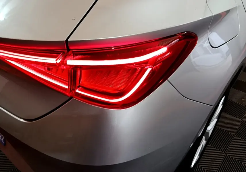 Gros plan sur le feu arrière droit rouge allumé d'une SEAT LEON gris foncé, avec la trappe à carburant visible.