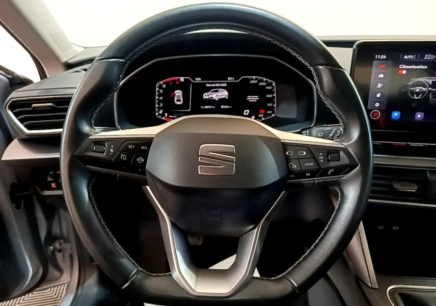 Vue rapprochée du volant cuir noir et du tableau de bord numérique du SEAT Leon 2023, intérieur moderne et épuré.