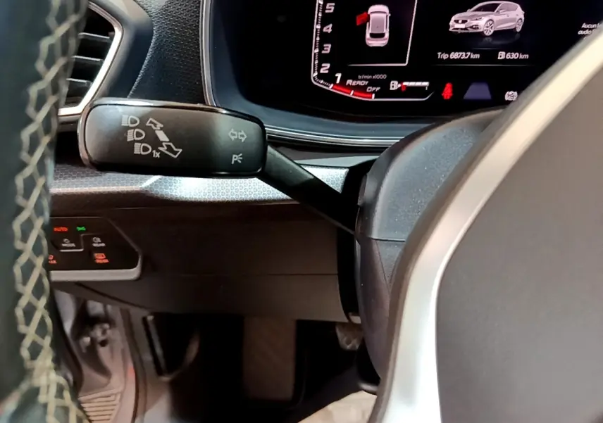 Gros plan sur la manette de clignotants à gauche du volant dans l’habitacle du SEAT Leon gris foncé 2023.