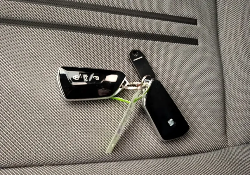 Gros plan sur une clé noire SEAT posée sur un siège gris clair en tissu à motifs fins.