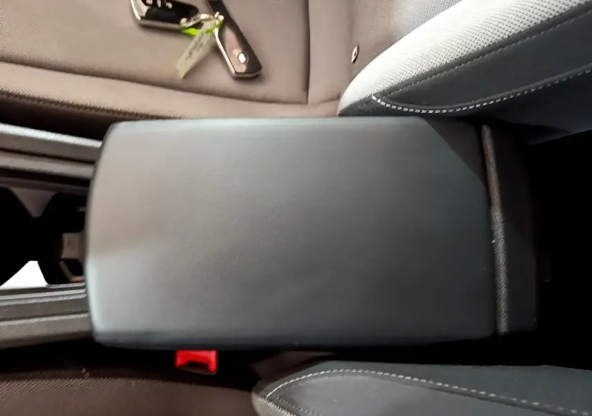 Accoudoir central noir en cuir dans l'habitacle d'une SEAT Leon gris foncé, avec clé posée sur le siège côté droit.