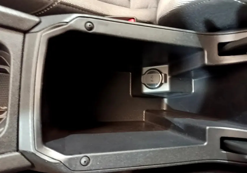 Gros plan sur la prise 12V dans le rangement central noir de la SEAT LEON 2023 version Business.