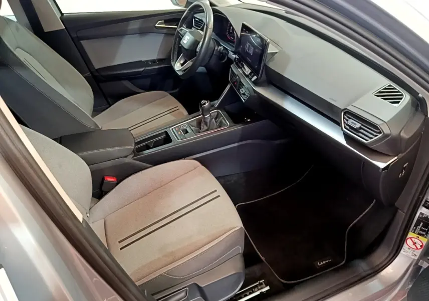 Intérieur avant droit de la SEAT Leon 2023 gris foncé, montrant sièges tissu, volant cuir et écran tactile central.