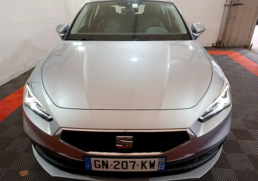 Vue frontale d'une SEAT LEON gris foncé avec phares LED allumés dans un garage fermé.