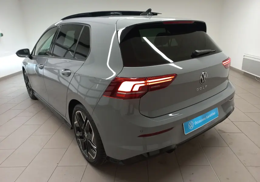 Vue 3/4 arrière droite d'une Volkswagen Golf 2.0 TDI R-Line gris lunaire avec toit ouvrant panoramique en intérieur showroom.