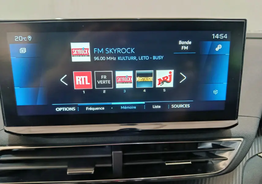 Écran tactile central du tableau de bord du Peugeot 3008 bleu, affichant les stations radio FM avec interface moderne.