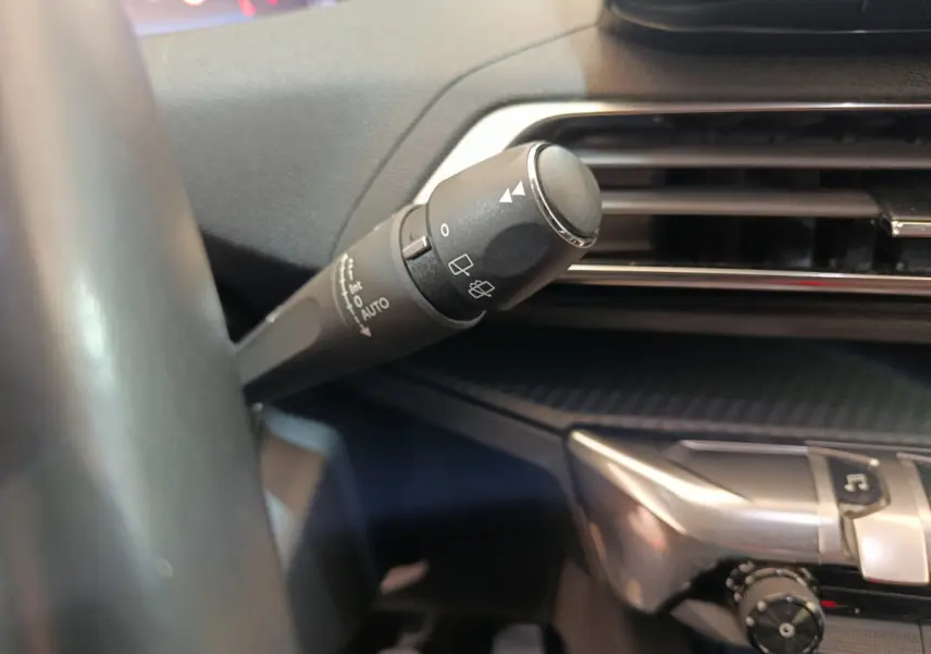 Gros plan sur la commande d'essuie-glace à gauche du volant dans l'habitacle du Peugeot 3008 bleu PureTech 2022.