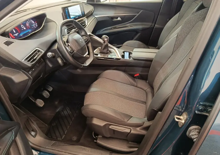 Vue intérieure côté conducteur du Peugeot 3008 bleu 2022, avec tableau de bord digital et volant cuir multifonctions.