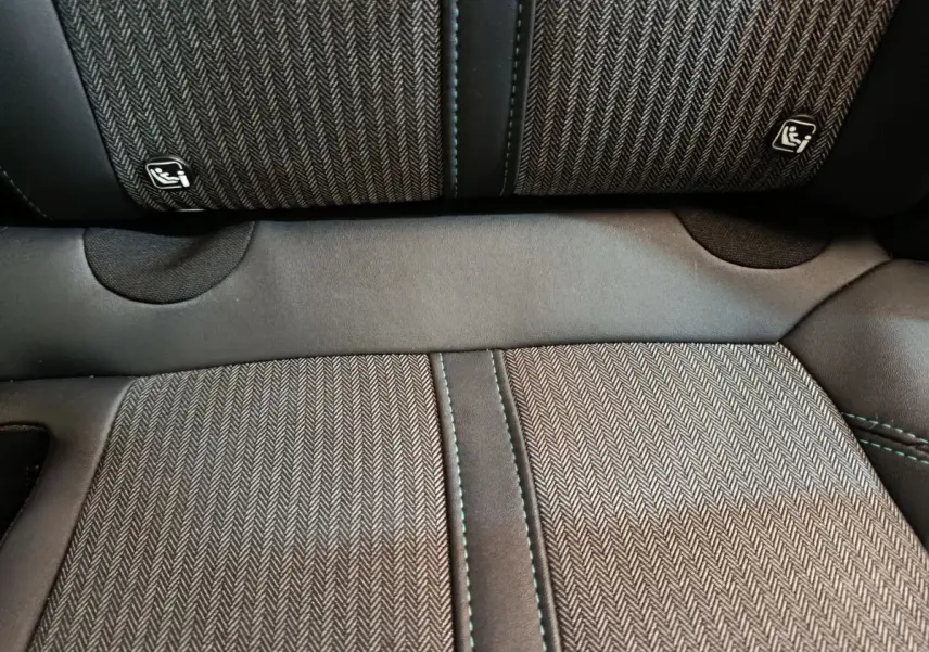 Gros plan sur la banquette arrière du Peugeot 3008 2022, tissu gris à motif chevrons avec coutures vertes et logos Isofix.