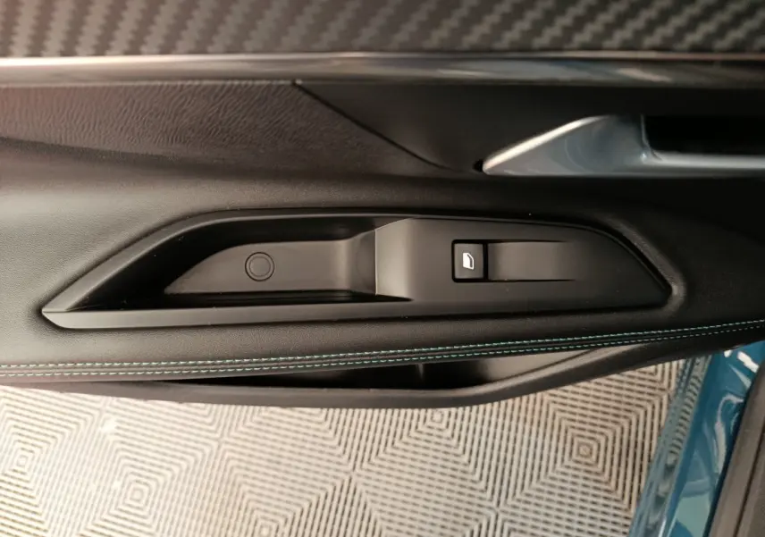 Gros plan sur la poignée intérieure et commande de vitre côté gauche d’un Peugeot 3008 bleu 2022.