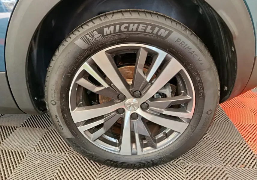 Gros plan sur la jante alliage et pneu Michelin d'un Peugeot 3008 bleu, côté droit avant.