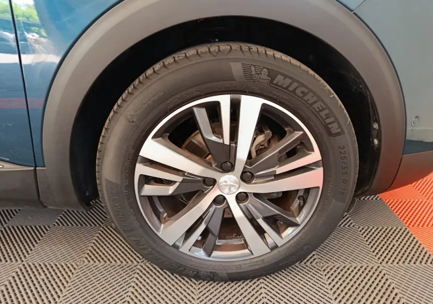 Gros plan sur la roue avant gauche du Peugeot 3008 bleu, mettant en valeur la jante alliage et le pneu Michelin.