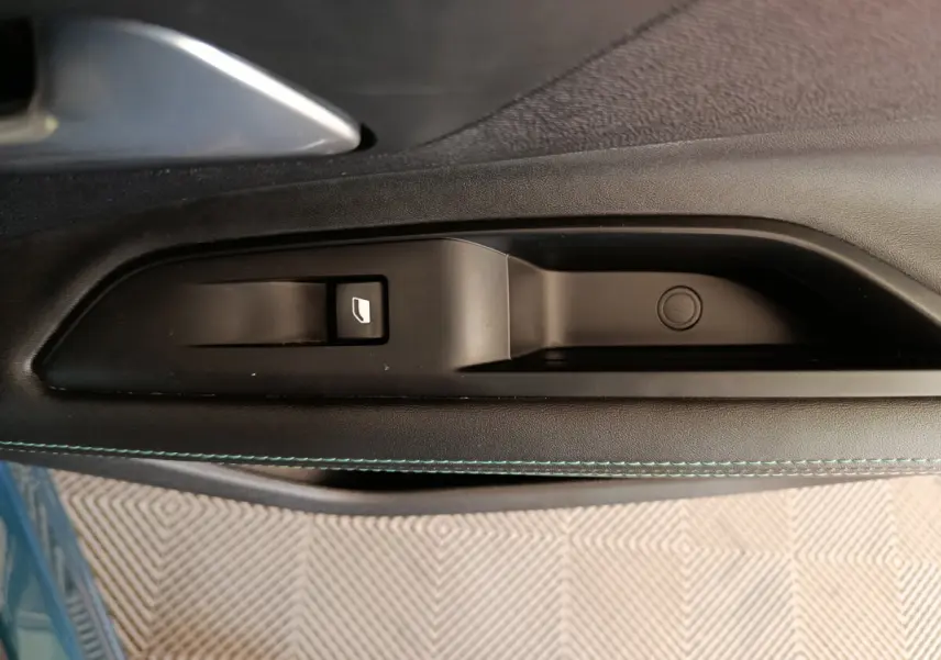 Gros plan sur la commande de lève-vitre côté gauche de la porte d'une Peugeot 3008 bleu 2022 PureTech Allure.