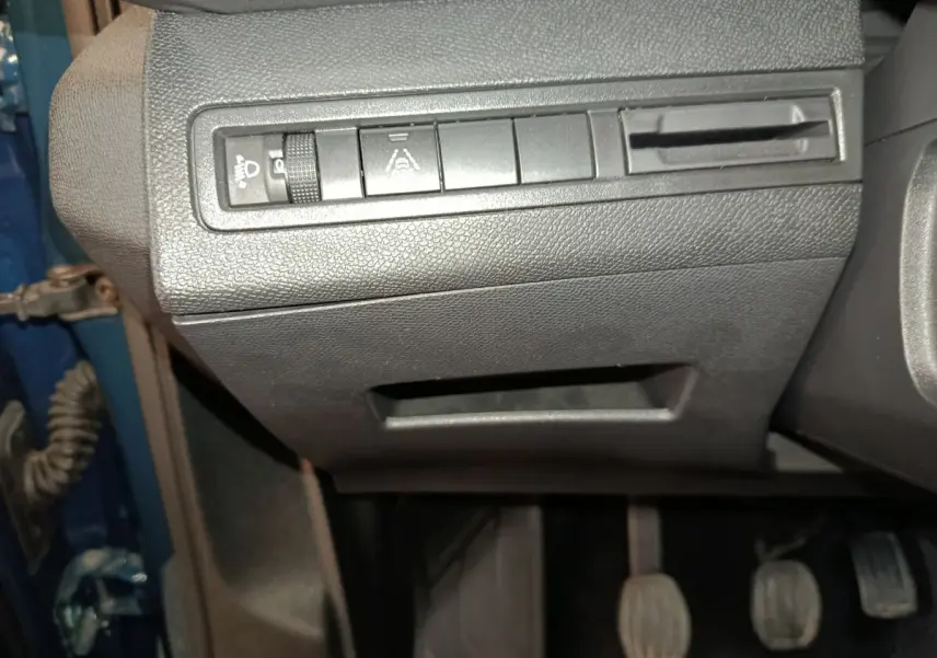 Gros plan sur les commandes sous le tableau de bord côté gauche d'un Peugeot 3008 bleu 2022.
