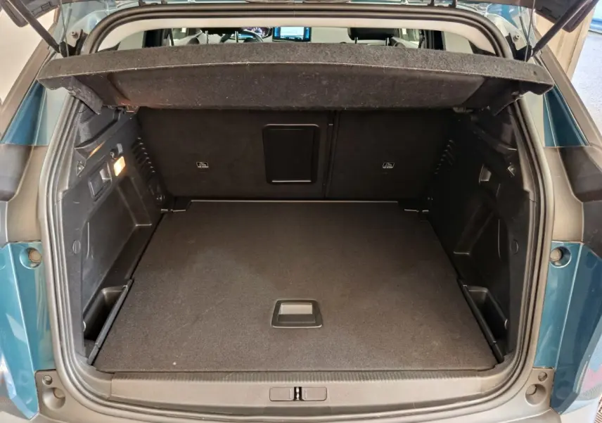 Coffre ouvert vu de l'arrière d'un Peugeot 3008 bleu 2022, espace de chargement propre et bien agencé.