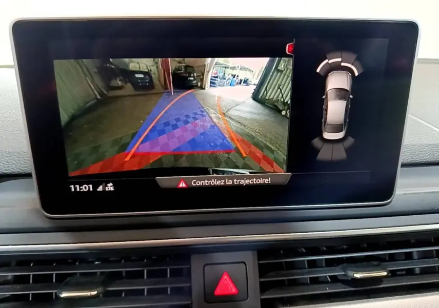 Écran central de l'Audi A4 noir 2018 montrant la caméra de recul et l'alerte de trajectoire en intérieur.