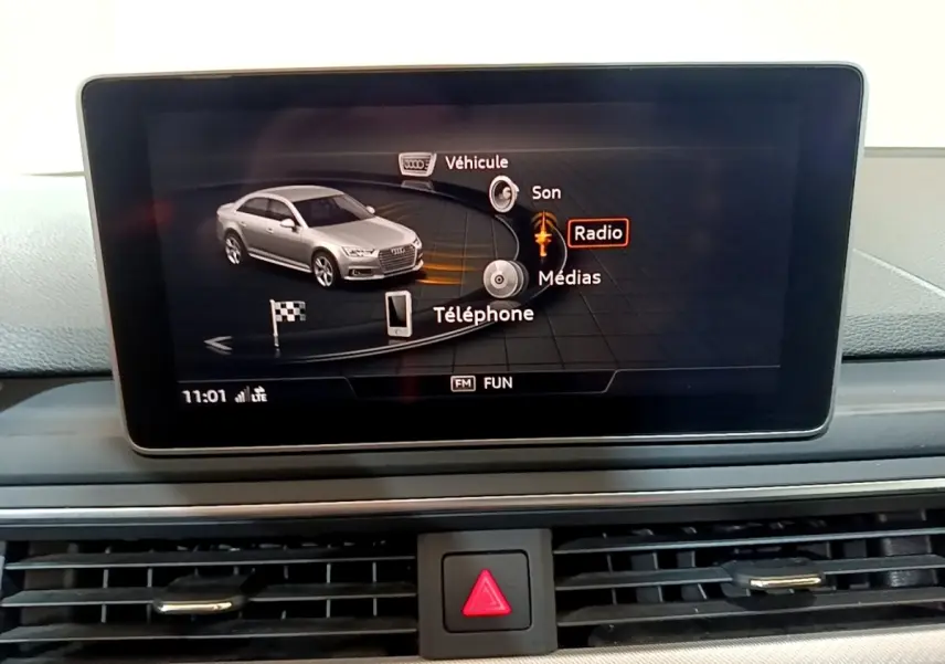 Écran tactile central affichant le menu multimédia avec une Audi A4 grise en illustration, vue intérieure.