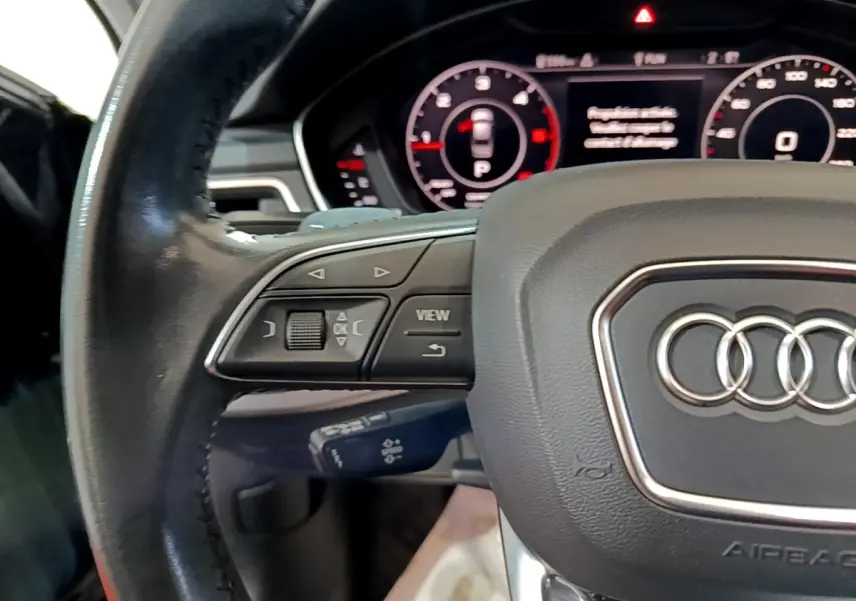 Gros plan sur le volant cuir noir de l'Audi A4 40 TDI 190 Quat S tronic Design Luxe avec commandes multifonctions visibles.