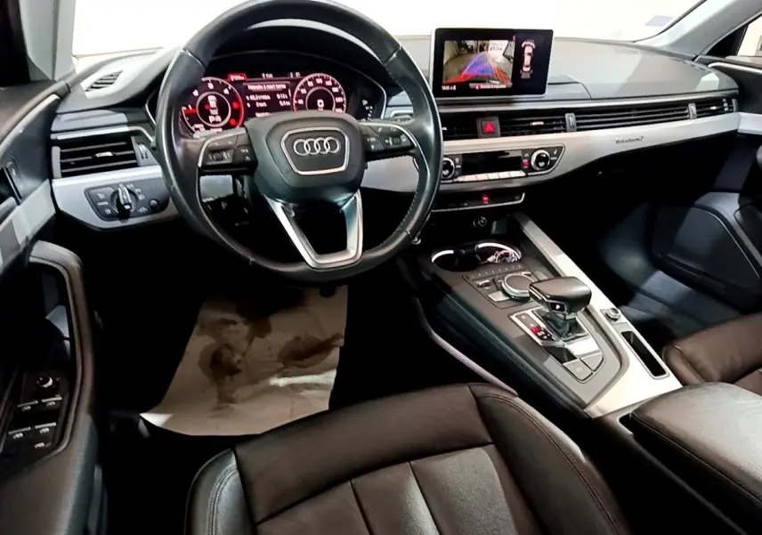 Vue intérieure de l'Audi A4 40 TDI 2018, tableau de bord et console centrale avec écran tactile et volant cuir noir.