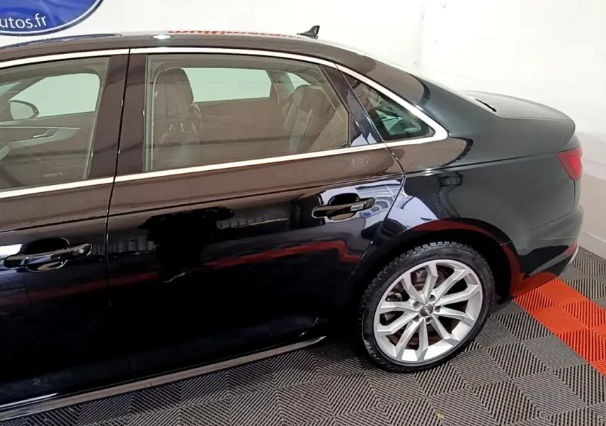 Vue latérale côté droit de l'Audi A4 noire 40 TDI 190 Quat S tronic Design Luxe, mettant en valeur la jante alliage et les lignes élégantes.