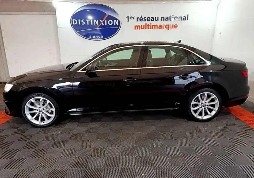 Profil côté gauche d'une Audi A4 noire 2018 Design Luxe, avec jantes alliage et vitres teintées en intérieur showroom.