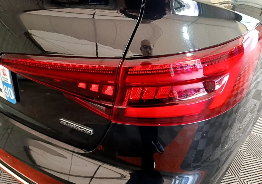 Gros plan sur le feu arrière droit rouge et la carrosserie noire brillante d'une Audi A4 40 TDI Quattro de 2018.