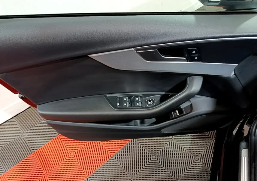 Vue rapprochée de la porte avant gauche noire d'une Audi A4 40 TDI 190 Quat S tronic Design Luxe avec commandes électriques.