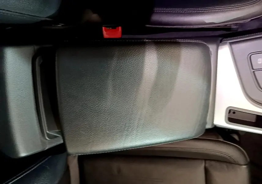 Gros plan sur l'accoudoir central noir en cuir et la console argentée de l'Audi A4 40 TDI 2018 côté conducteur.