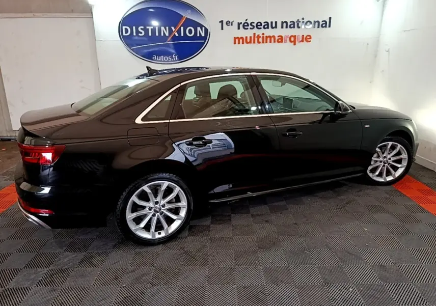 Audi A4 noire vue de profil côté gauche dans un showroom avec jantes alliage et vitres teintées.