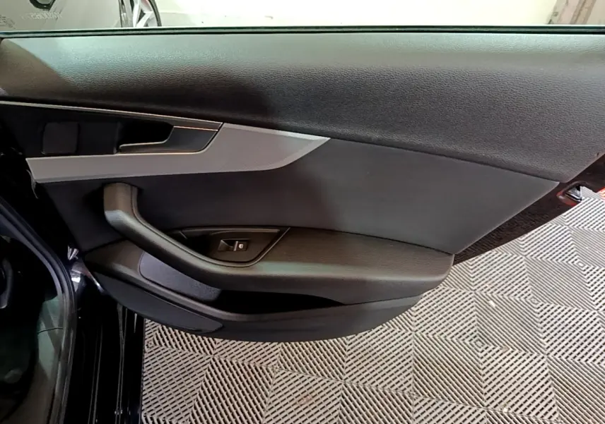 Vue rapprochée de la porte arrière gauche noire d'une Audi A4 40 TDI 2018, avec poignée et commande de vitre.