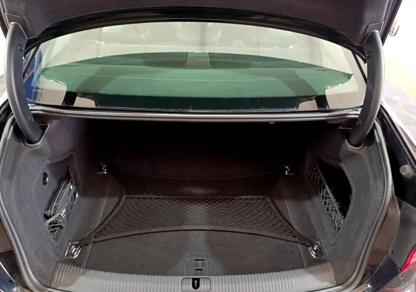 Vue du coffre ouvert de l'Audi A4 noire 2018, montrant l'espace de rangement avec filet de maintien et garniture noire.