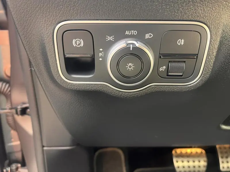Gros plan sur les commandes d’éclairage et frein de stationnement du Mercedes GLA 200 d AMG Line gris montagne magno.