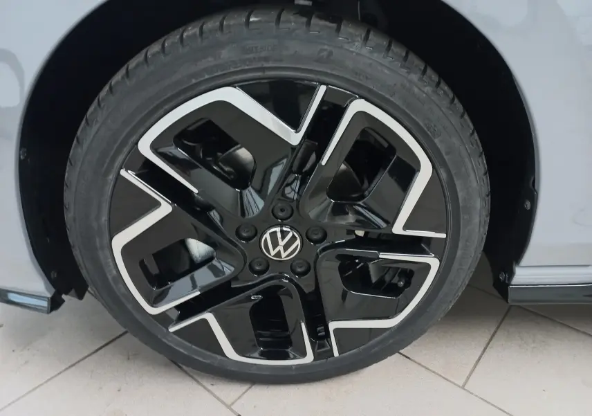 Gros plan sur la jante noire et argentée d’une Volkswagen Golf gris lunaire, côté droit, avec logo VW central.
