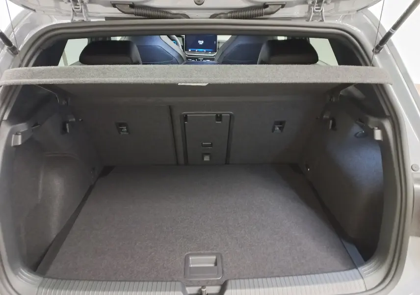 Vue intérieure du coffre ouvert de la Volkswagen Golf gris lunaire, montrant l’espace de chargement et la tablette arrière.