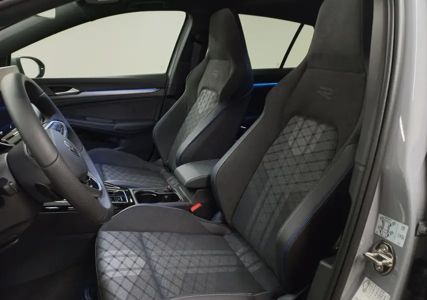 Vue intérieure côté conducteur de la Volkswagen Golf 2.0 TDI R-Line 2026 avec sièges sport en tissu gris et surpiqûres bleues.