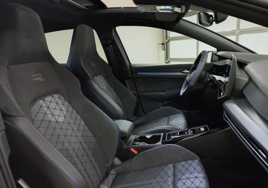 Vue intérieure côté conducteur de la Volkswagen Golf 2.0 TDI R-Line, sièges en tissu noir avec surpiqûres bleues et toit ouvrant.