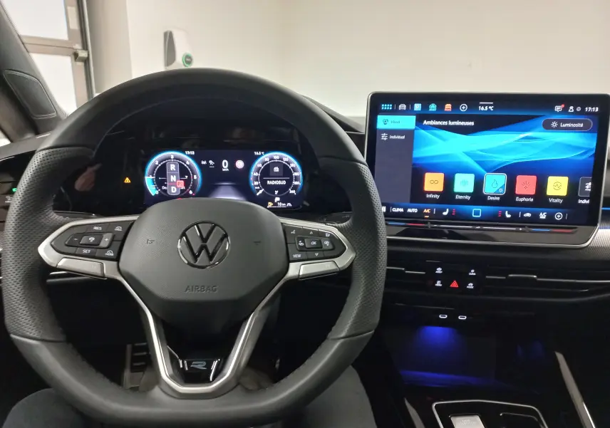 Vue intérieure centrée sur le volant multifonction cuir et l'écran tactile du tableau de bord de la Volkswagen Golf gris lunaire.