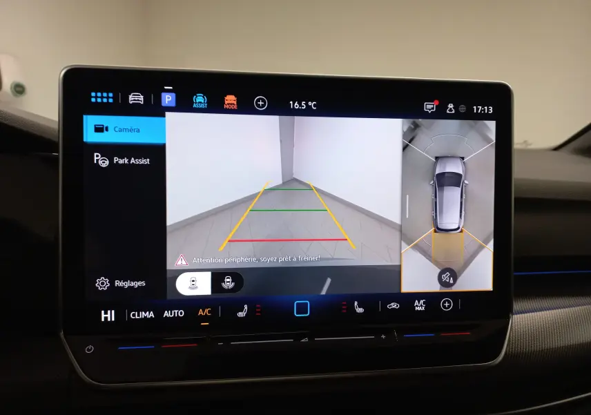 Vue intérieure de l'écran tactile affichant la caméra 360° d'une Volkswagen Golf gris lunaire en marche arrière.