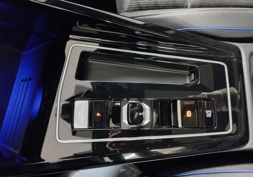 Vue rapprochée de la console centrale noire brillante de la Volkswagen Golf 2.0 TDI 150 DSG7 R-Line avec commandes de boîte auto.